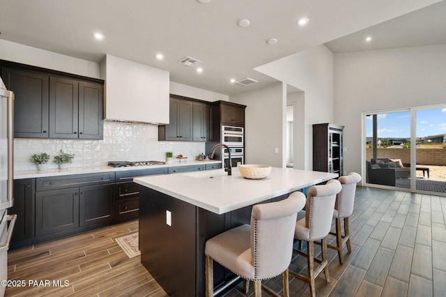 5711 E Hahn St, Prescott Valley, AZ 86314 - kitchen with stainless steel gas cooktop, light wood-type flooring, backsplash, light countertops, and an island with sink