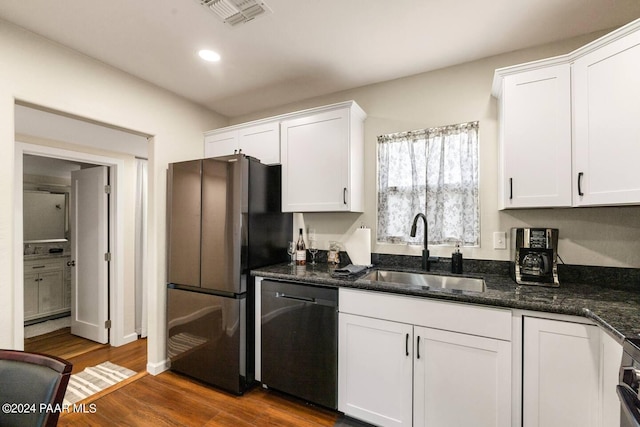 kitchen with appliances with stainless steel finishes, dark wood-type flooring, sink, dark stone countertops, and white cabinets