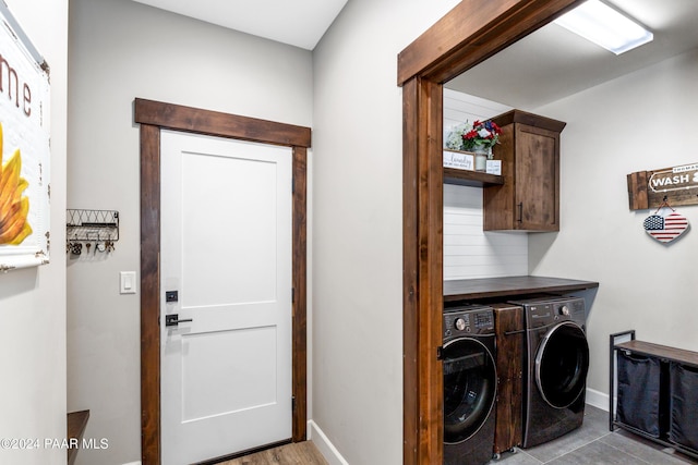 washroom featuring washer and clothes dryer, cabinet space, and baseboards