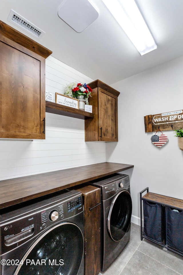 clothes washing area featuring visible vents, separate washer and dryer, cabinet space, and baseboards