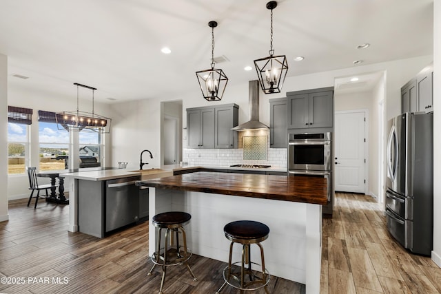 9550 N Manger Rd, Prescott Valley, AZ 86314 - kitchen with appliances with stainless steel finishes, wooden counters, wall chimney range hood, gray cabinetry, and a center island