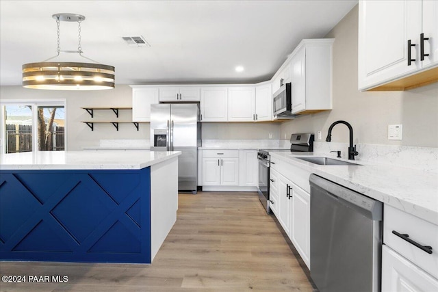 kitchen featuring appliances with stainless steel finishes, sink, pendant lighting, white cabinets, and a chandelier