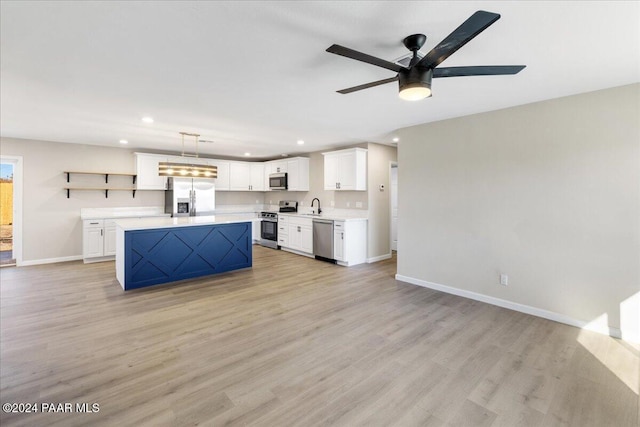 kitchen featuring pendant lighting, light wood-type flooring, appliances with stainless steel finishes, a kitchen island, and white cabinetry