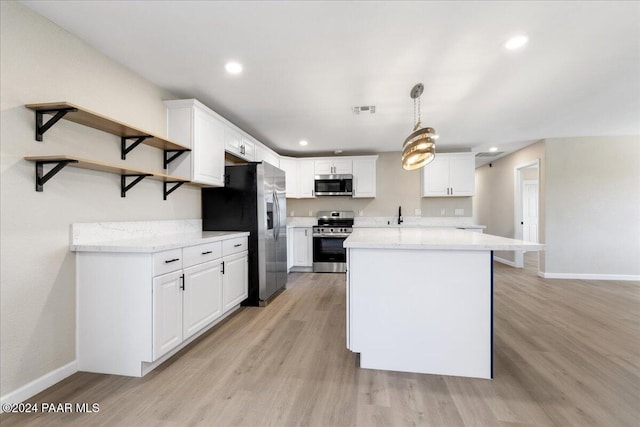 kitchen featuring hanging light fixtures, white cabinets, stainless steel appliances, and light hardwood / wood-style floors