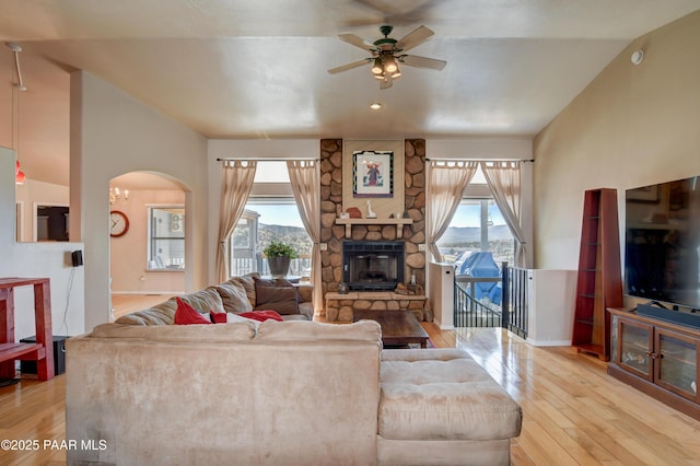 living room featuring ceiling fan, plenty of natural light, a fireplace, and light hardwood / wood-style floors