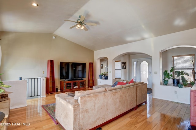 living room with ceiling fan, vaulted ceiling, and light wood-type flooring