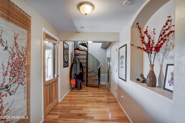 corridor with light hardwood / wood-style floors and a textured ceiling