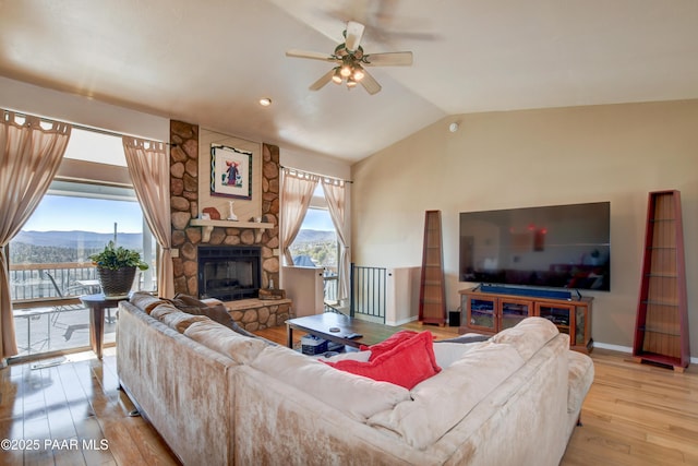 living room with a fireplace, lofted ceiling, ceiling fan, light hardwood / wood-style floors, and a mountain view