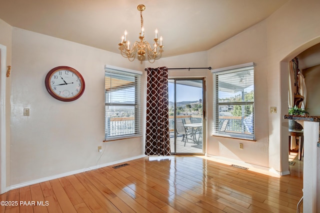 unfurnished dining area featuring lofted ceiling, light hardwood / wood-style floors, and a notable chandelier