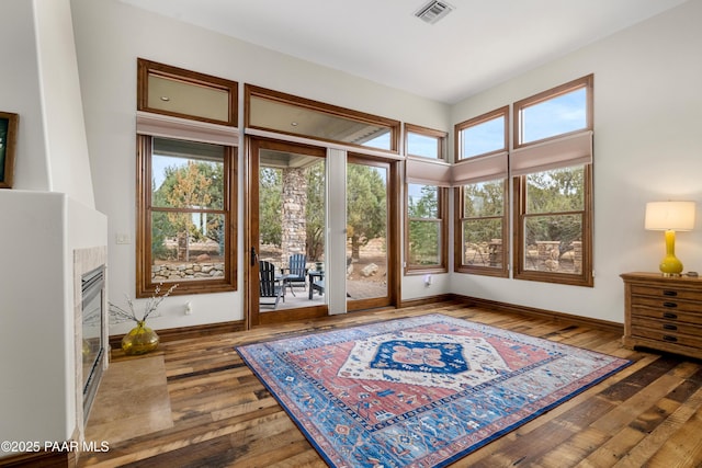 interior space with hardwood / wood-style flooring, plenty of natural light, and a tile fireplace