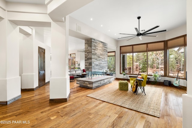 interior space featuring a high ceiling, light wood-type flooring, decorative columns, and ceiling fan