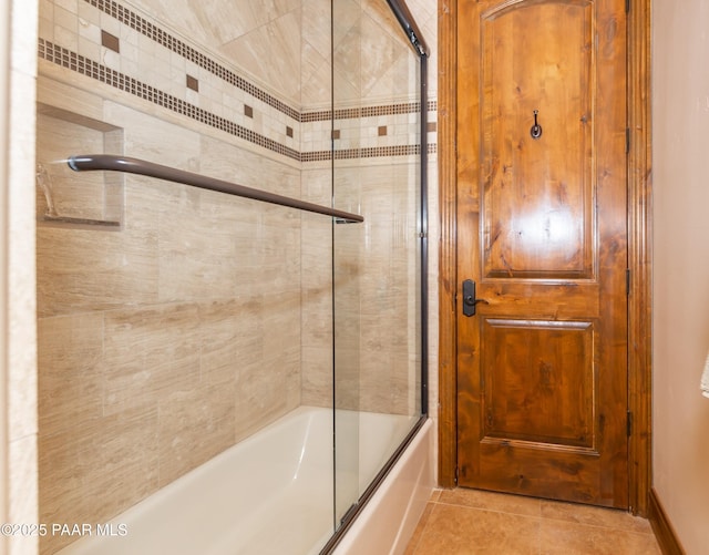 bathroom featuring tile patterned flooring and shower / bath combination with glass door