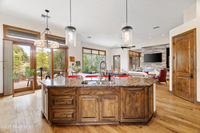 kitchen with an island with sink, decorative light fixtures, and sink