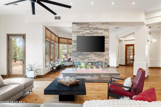 living room featuring ceiling fan, a fireplace, and light wood-type flooring