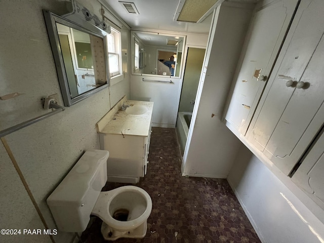 bathroom featuring vanity, a tub to relax in, and toilet