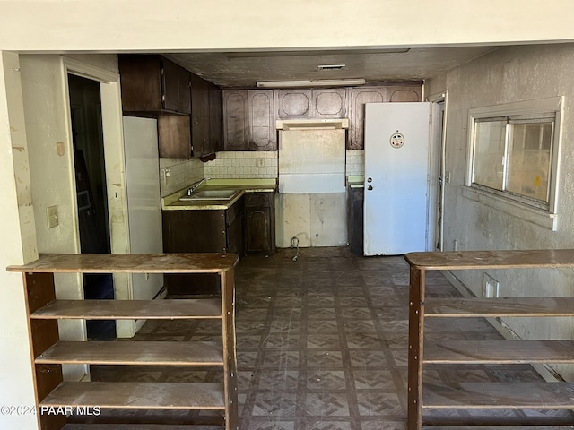 kitchen featuring decorative backsplash, dark brown cabinetry, and sink