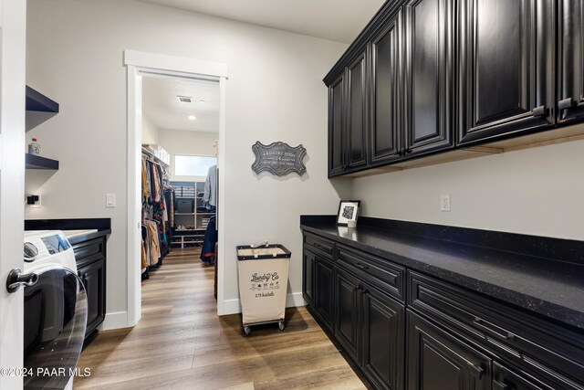 kitchen featuring dark countertops, light wood finished floors, washer / clothes dryer, and dark cabinetry