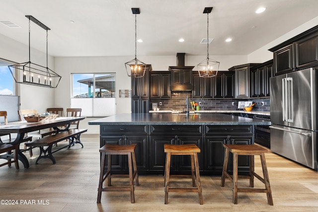 kitchen featuring light wood finished floors, tasteful backsplash, visible vents, high quality fridge, and a sink