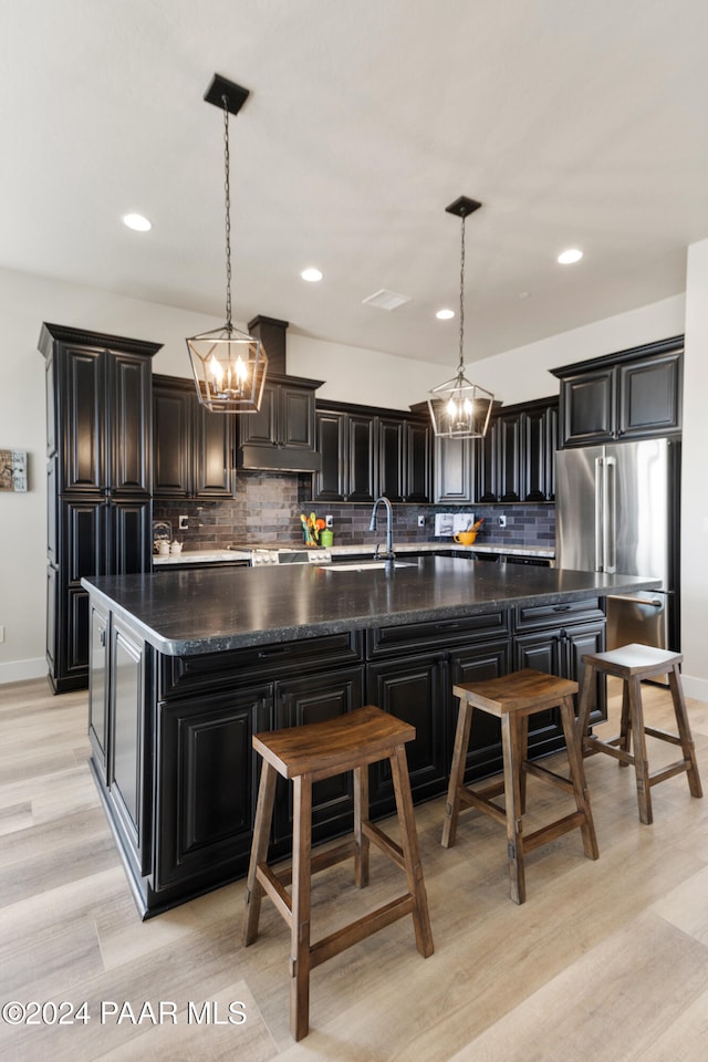 kitchen with hanging light fixtures, a spacious island, tasteful backsplash, and freestanding refrigerator