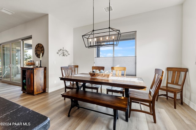 dining area with baseboards, a chandelier, visible vents, and light wood-style floors