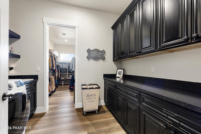 kitchen with dark countertops, light wood-type flooring, washer / dryer, and dark cabinets