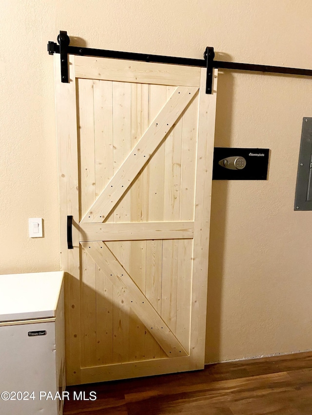 details featuring a barn door, hardwood / wood-style floors, and electric panel