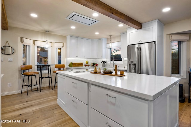 kitchen with a center island, high end fridge, white cabinets, and decorative light fixtures