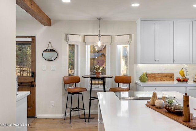 dining space with beam ceiling and light hardwood / wood-style floors