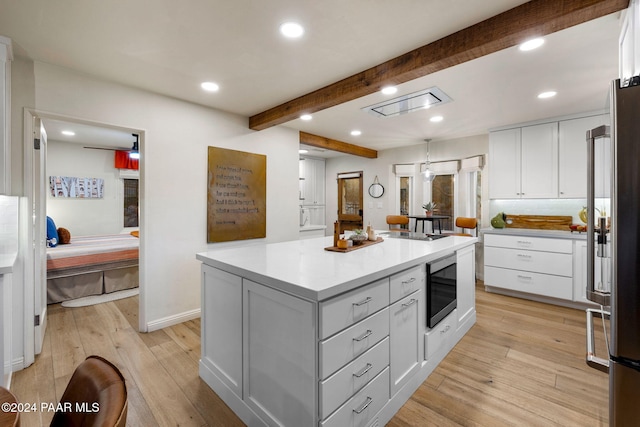 kitchen with white cabinets, a kitchen island, light wood-type flooring, and stainless steel appliances