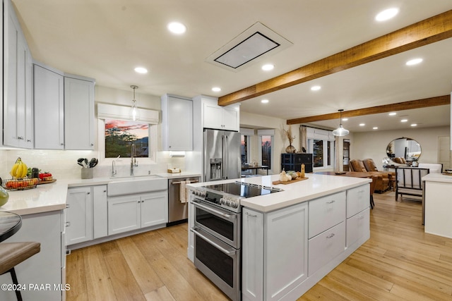 kitchen with light hardwood / wood-style floors, white cabinets, pendant lighting, and appliances with stainless steel finishes