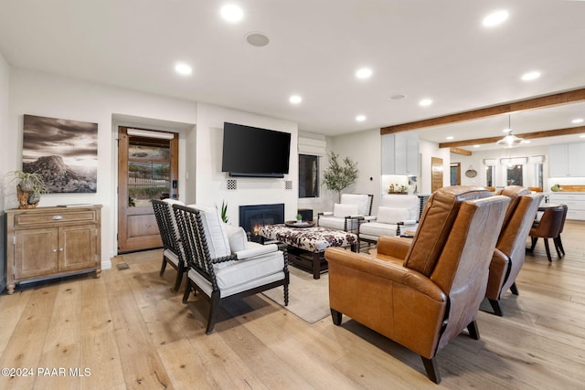 living room featuring ceiling fan, beam ceiling, and light hardwood / wood-style flooring