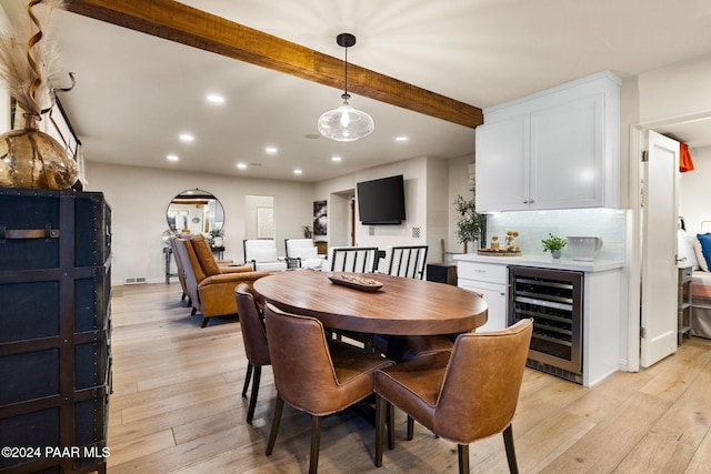 dining area featuring beam ceiling, light hardwood / wood-style flooring, and beverage cooler