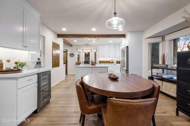 dining room with beam ceiling, light hardwood / wood-style floors, and beverage cooler