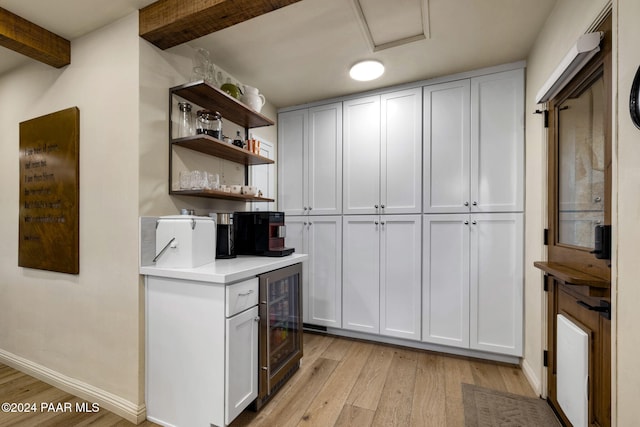 kitchen featuring wine cooler, beamed ceiling, white cabinets, and light hardwood / wood-style floors