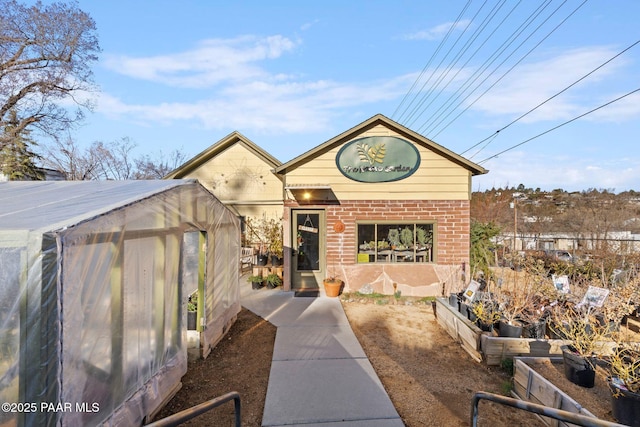 view of front of home with an outbuilding, a vegetable garden, and brick siding