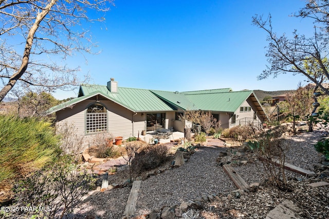 rear view of property with a chimney, a patio, and metal roof