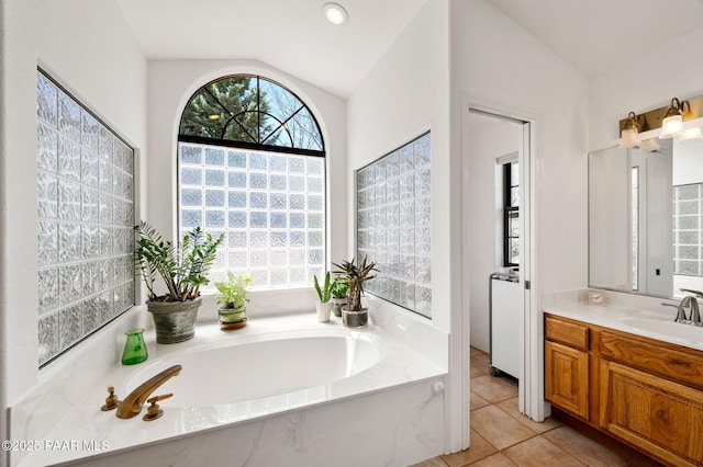 bathroom with a bath, lofted ceiling, a healthy amount of sunlight, and vanity