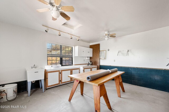 interior space with concrete floors, rail lighting, and ceiling fan