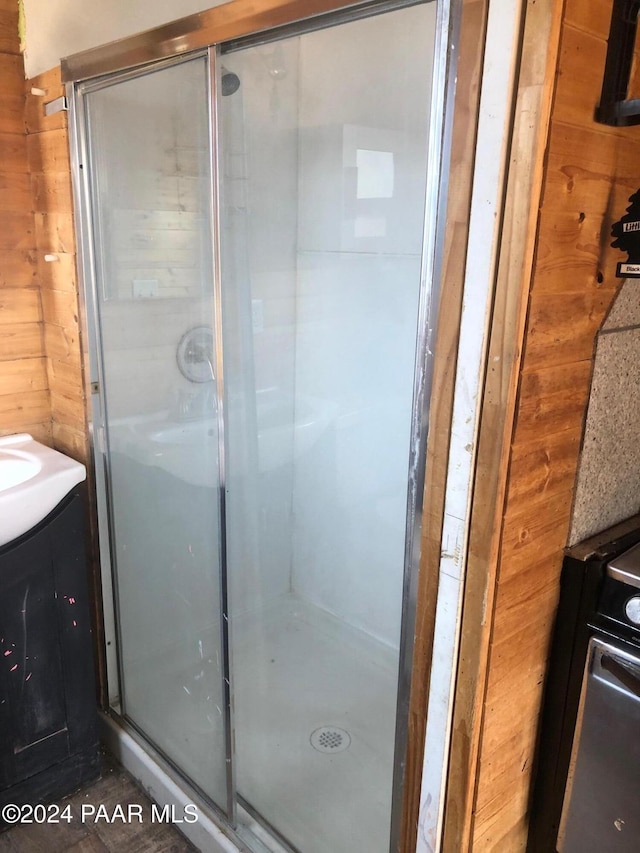 bathroom featuring vanity, wood walls, and an enclosed shower