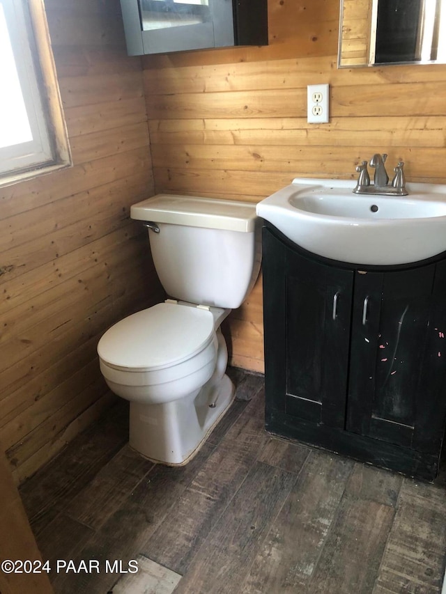 bathroom with wood-type flooring, vanity, toilet, and wood walls