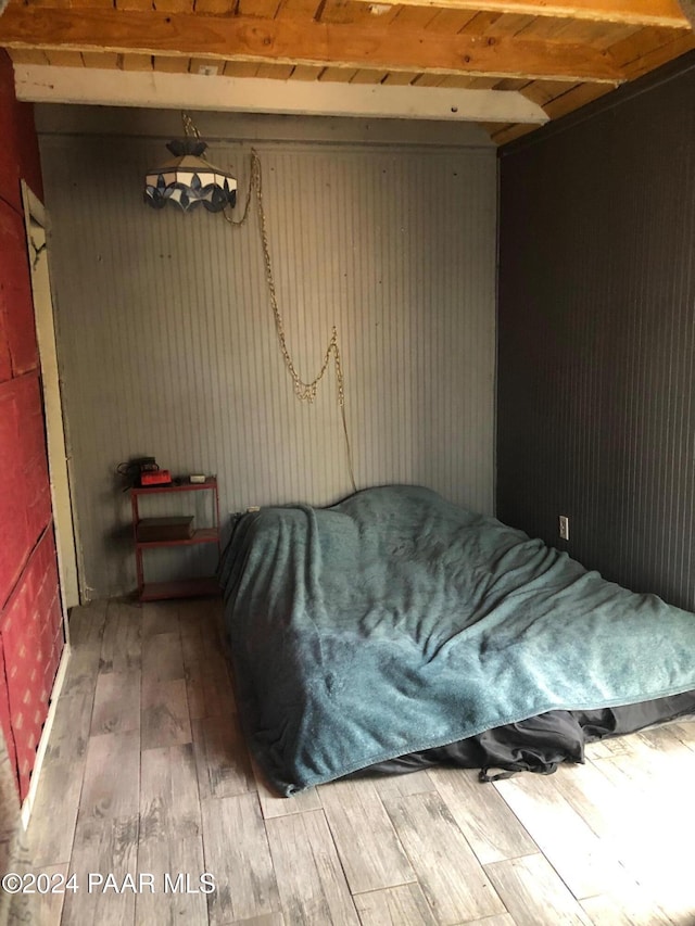 unfurnished bedroom with beamed ceiling and wood-type flooring