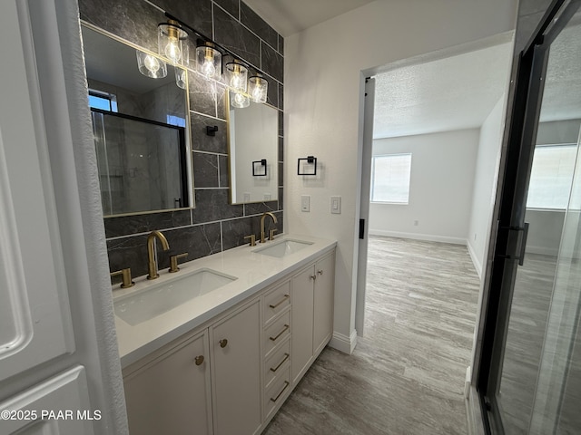 full bathroom with a sink, decorative backsplash, wood finished floors, and a stall shower