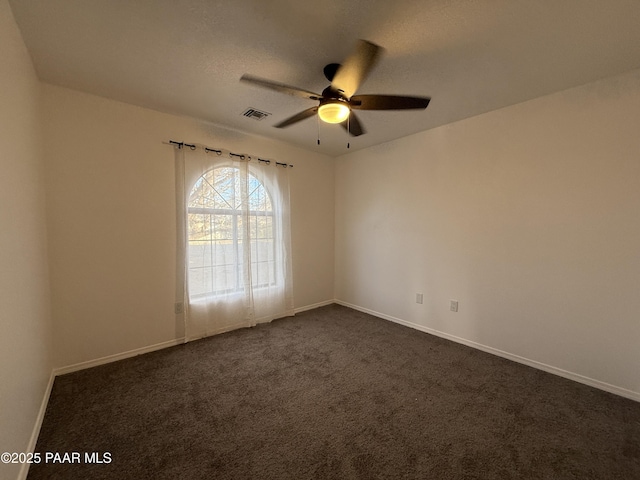 empty room with visible vents, baseboards, ceiling fan, and dark carpet