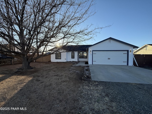 view of front of property with concrete driveway, an attached garage, and fence