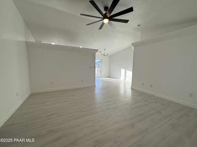 empty room featuring light wood-type flooring, ceiling fan with notable chandelier, a textured ceiling, baseboards, and lofted ceiling