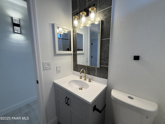 bathroom with vanity, toilet, and a textured wall