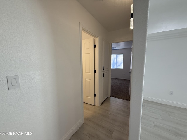 hall with baseboards and light wood-style flooring