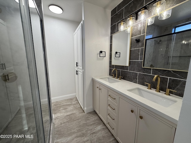 bathroom featuring backsplash, a shower stall, wood finished floors, and a sink