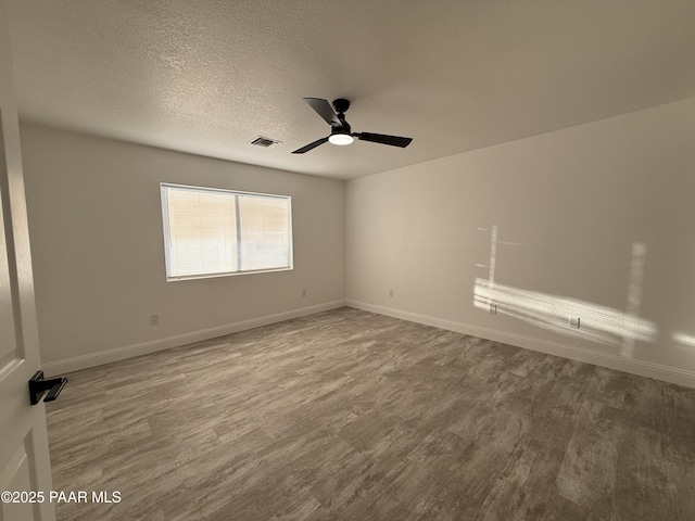 unfurnished room featuring a ceiling fan, baseboards, wood finished floors, visible vents, and a textured ceiling