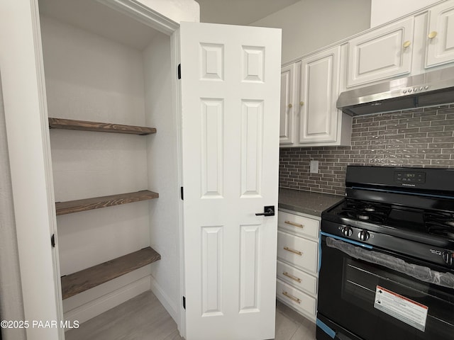 kitchen with backsplash, range hood, white cabinets, and black stove